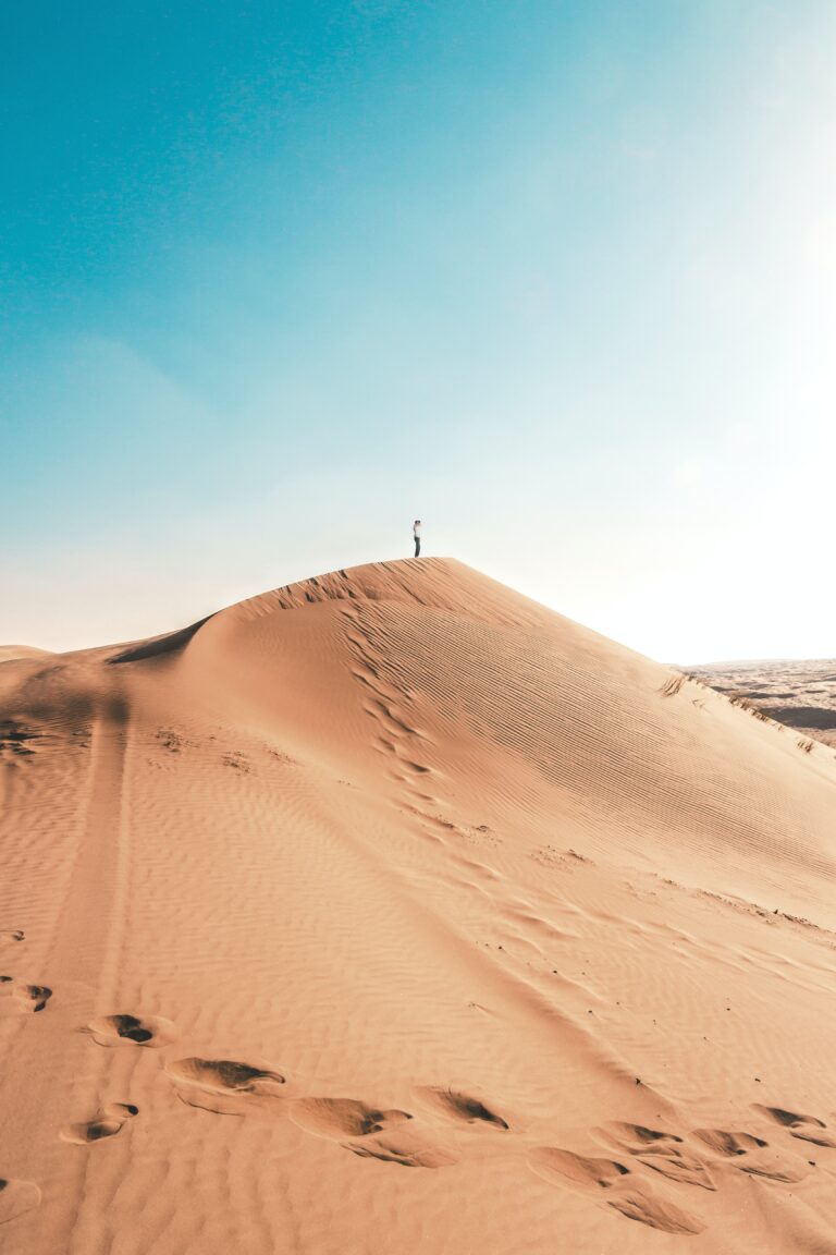 man standing on sand dune
