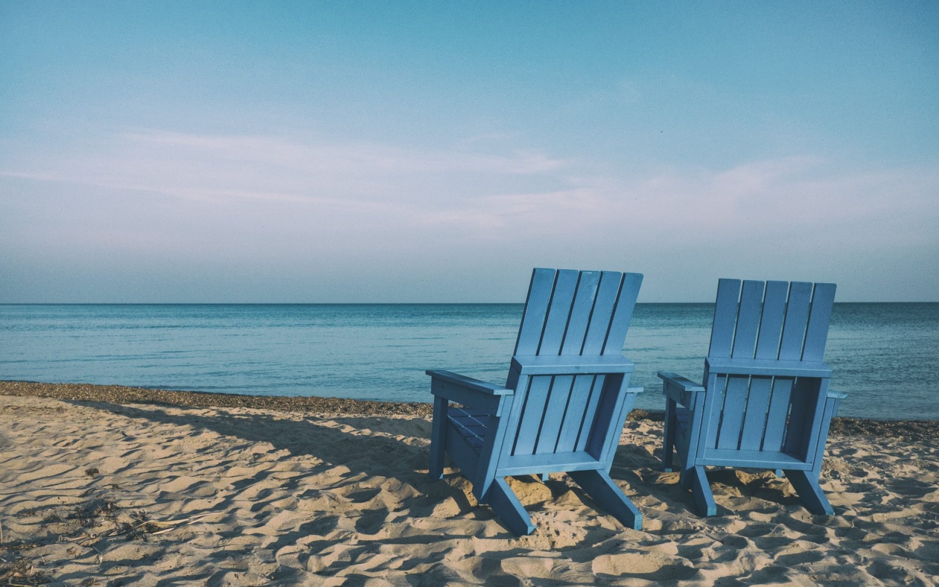 two blue beach chairs near body of water